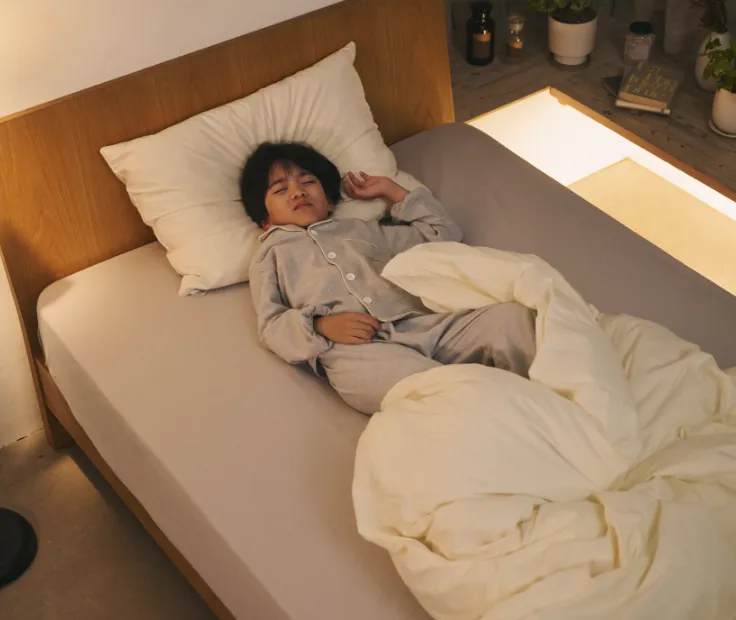 掛け布団を蹴り飛ばして眠る子どものイメージ写真
